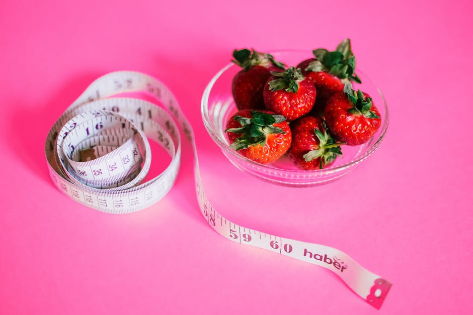 measuring tape beside a bowl of strawberries