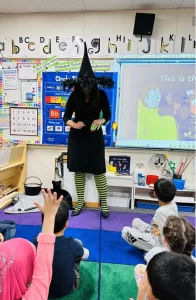 Becky Grant dressed as a witch teaching kids her Halloween song.